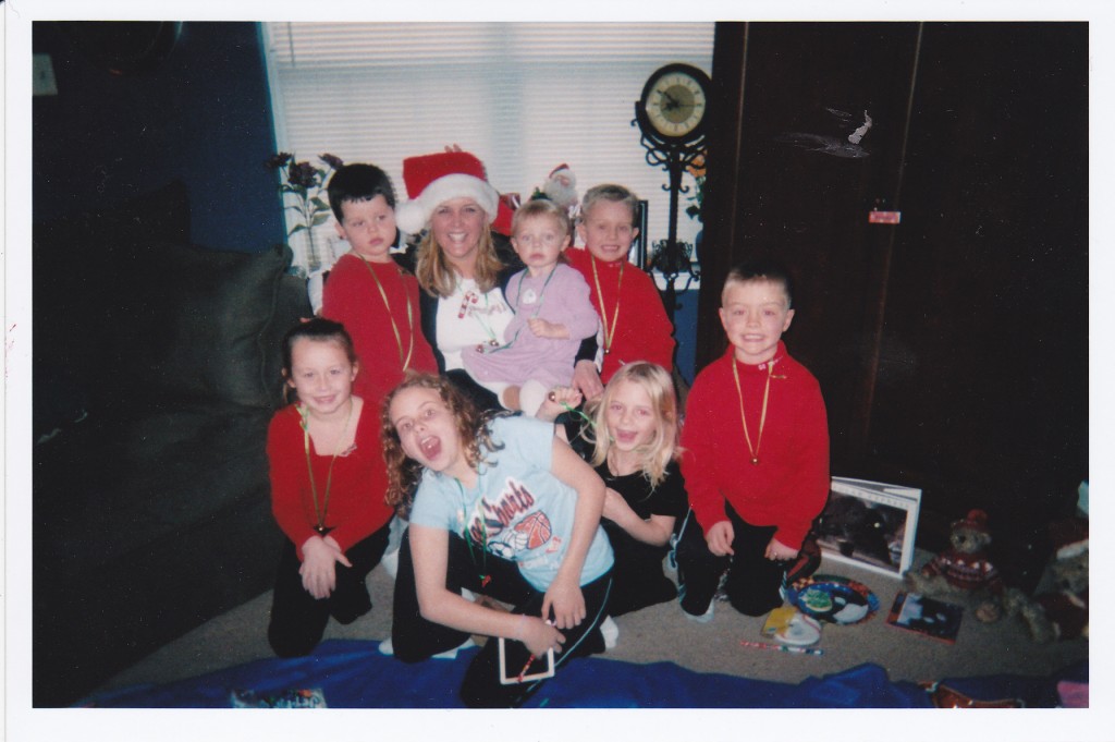 woman with santa hat on and many kids around her