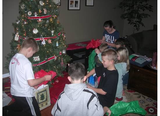 kids opening presents by a tree