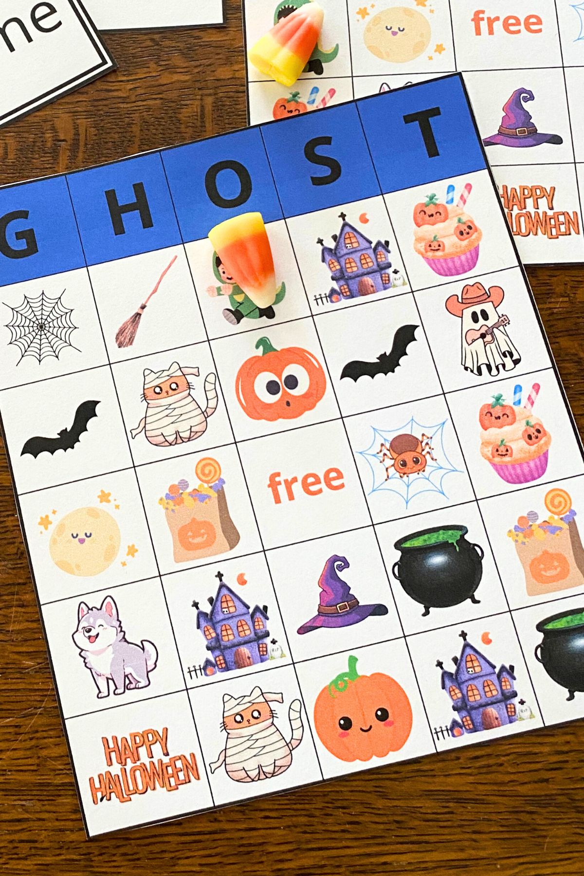 Ghost Bingo printable of a single bingo board with colorful cartoon Halloween images and smaller printed cards with the same characters on each card.