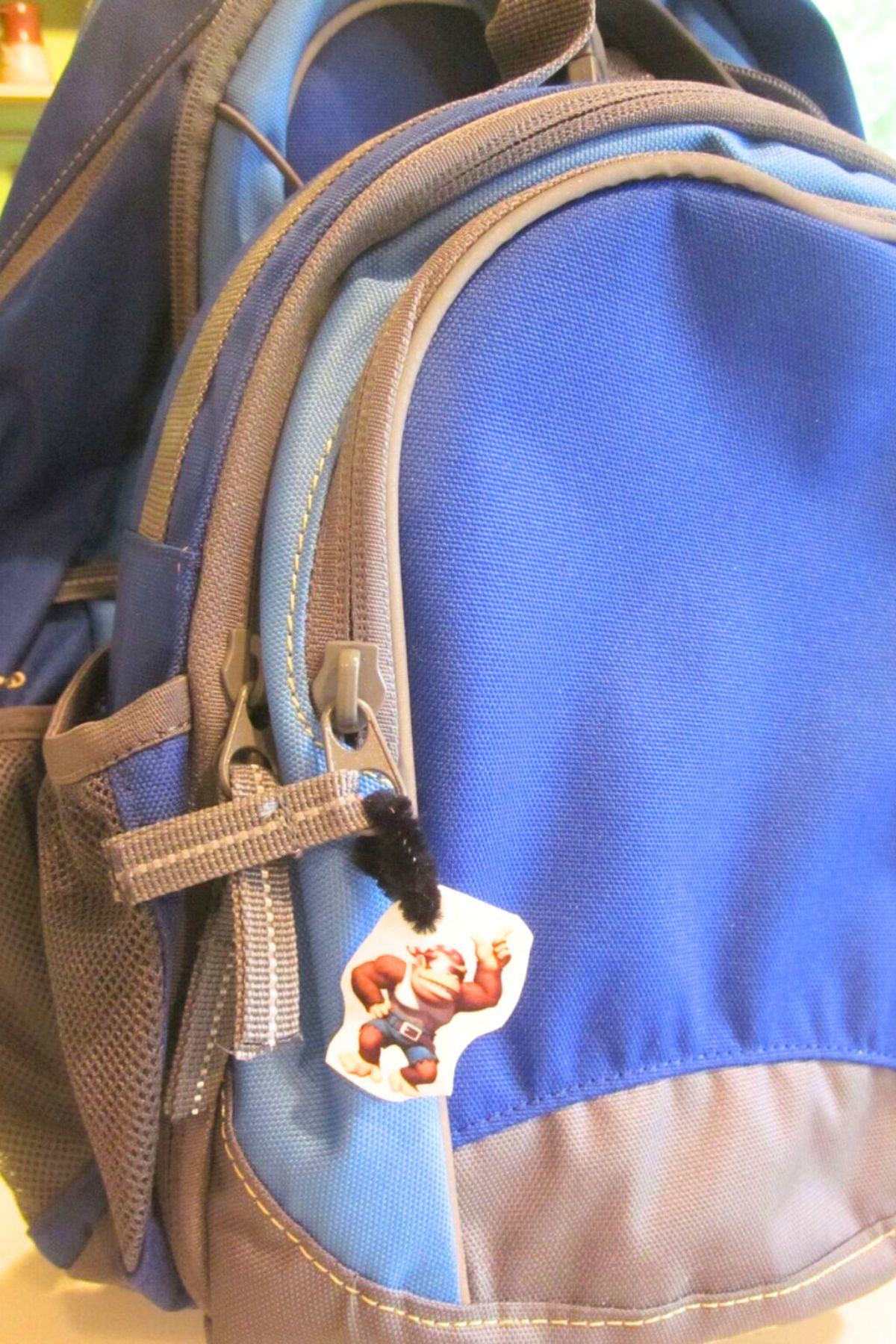 Blue backpack with a shrinky-dink tag on the zipper pull