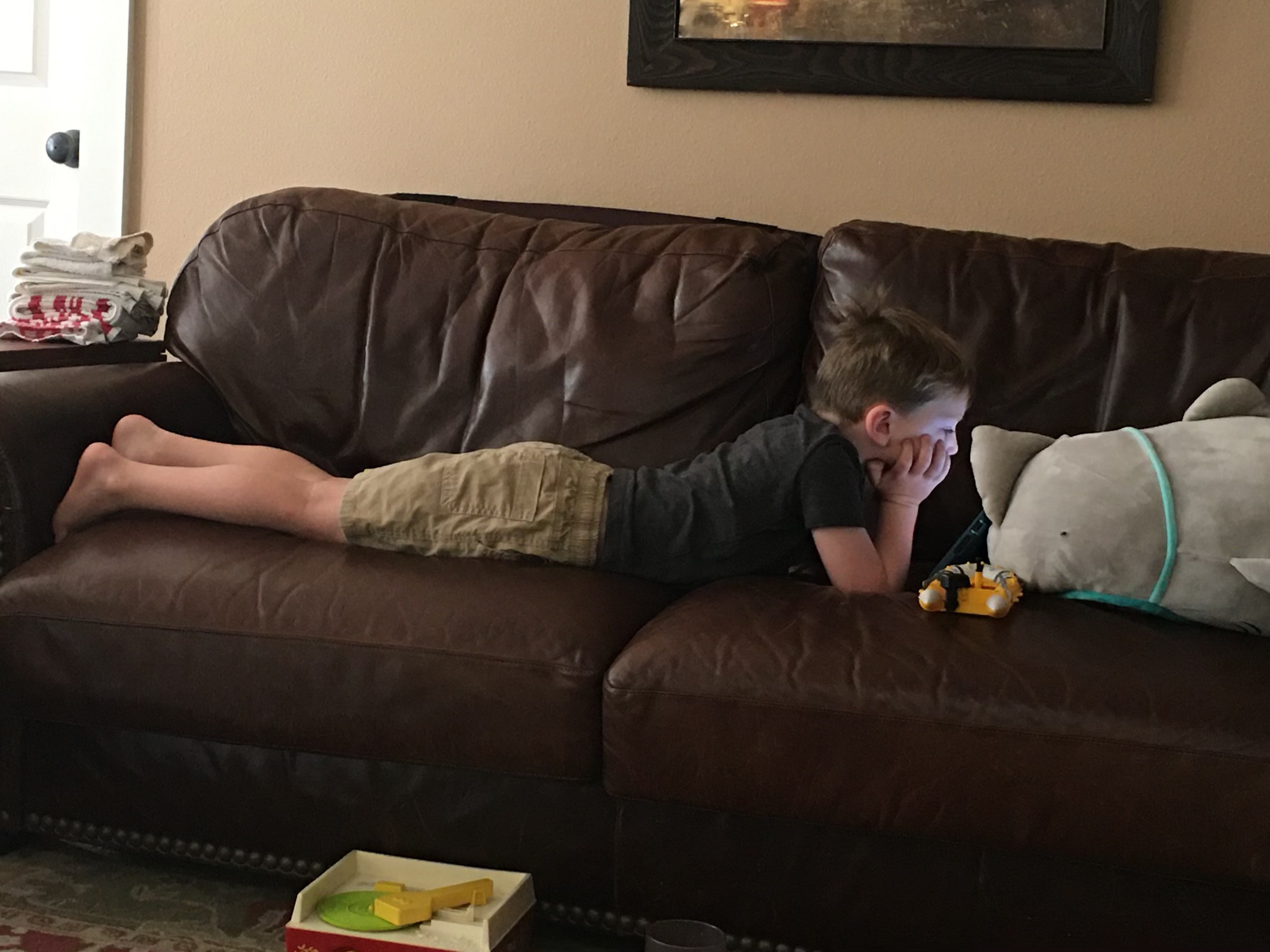 Young boy laying on a couch reading