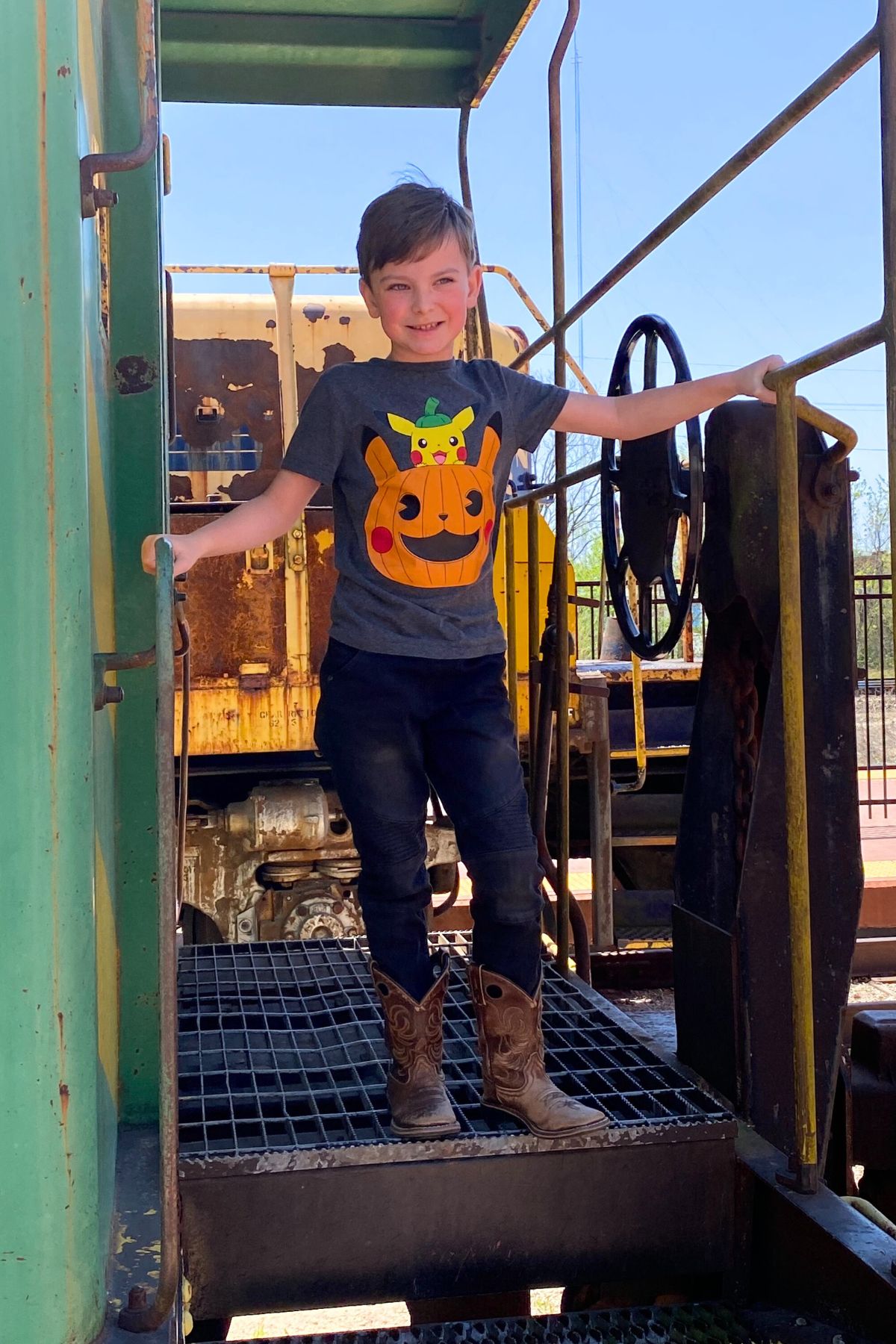 Child wearing a tee shirt with a printed pumpkin standing on a train car