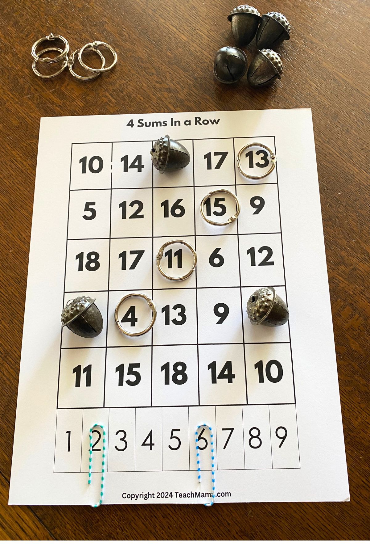 White cardstock with five columns of numbers with jump rings and metal acorns for markers