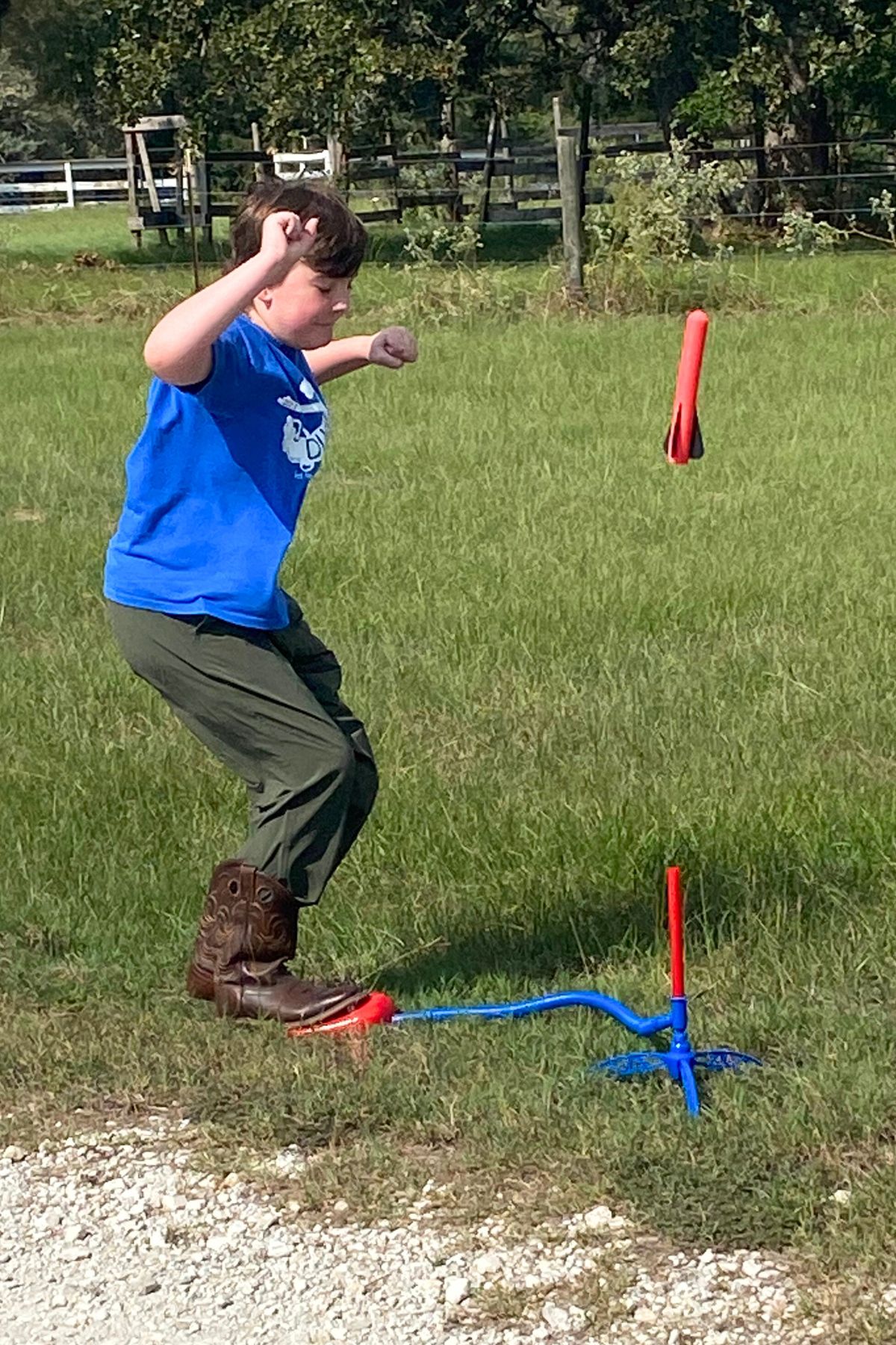 Boy in a blue shirt launching a red air-powered stomp rocket