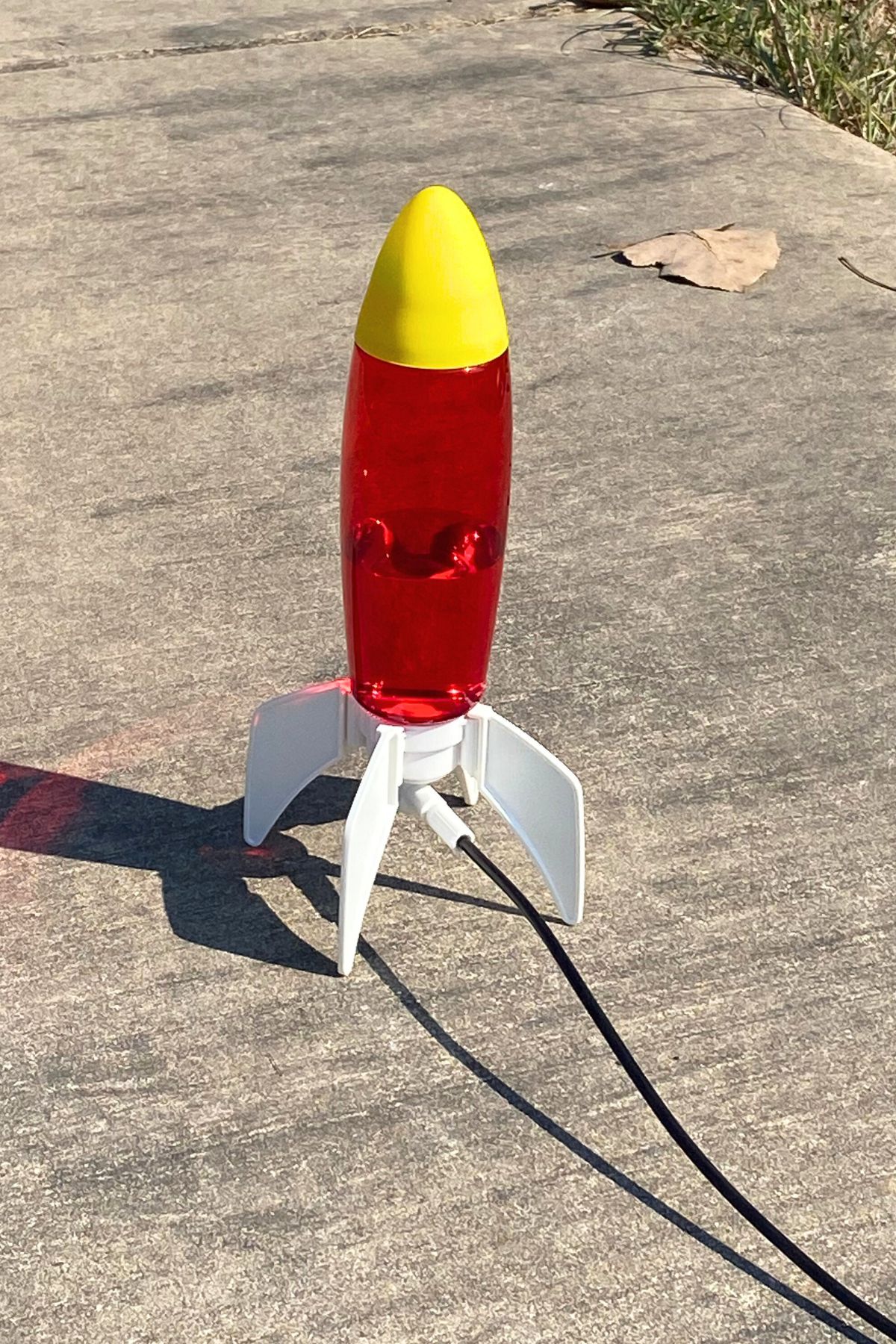 Water rocket with red plastic body, yellow nose cone and white fins