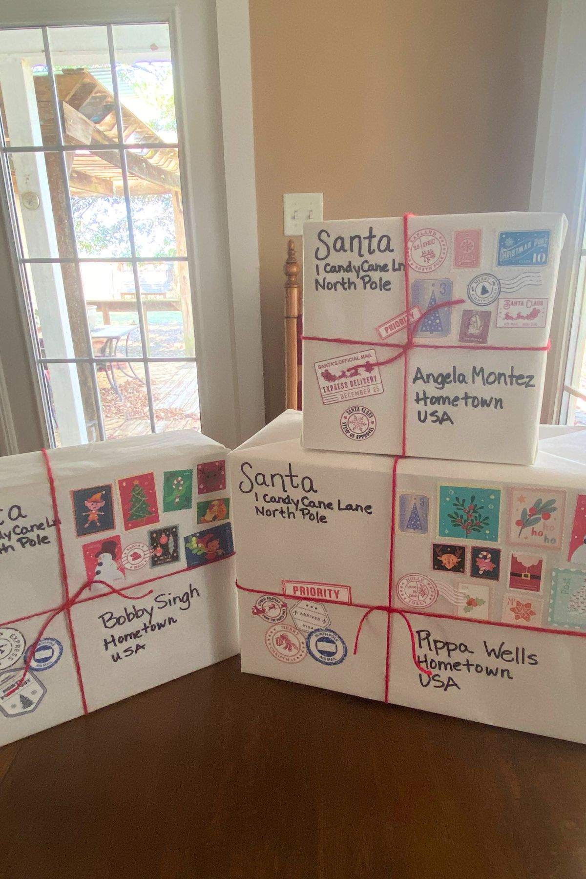 Boxes wrapped in white paper with red yarn ribbon and North Pole postal marks