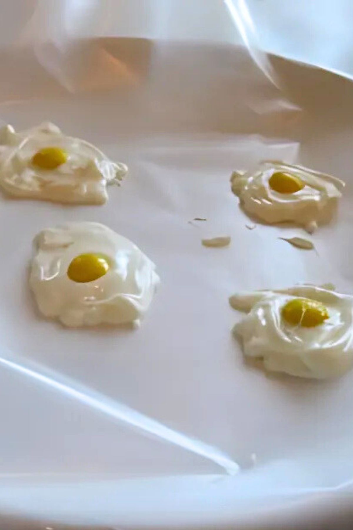 White chocolate "egg" whites with M&M yolks on wax paper