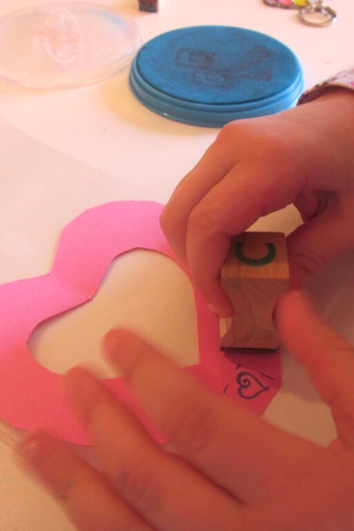 Child's hand stamping around the edge of a heart cut out of construction paper