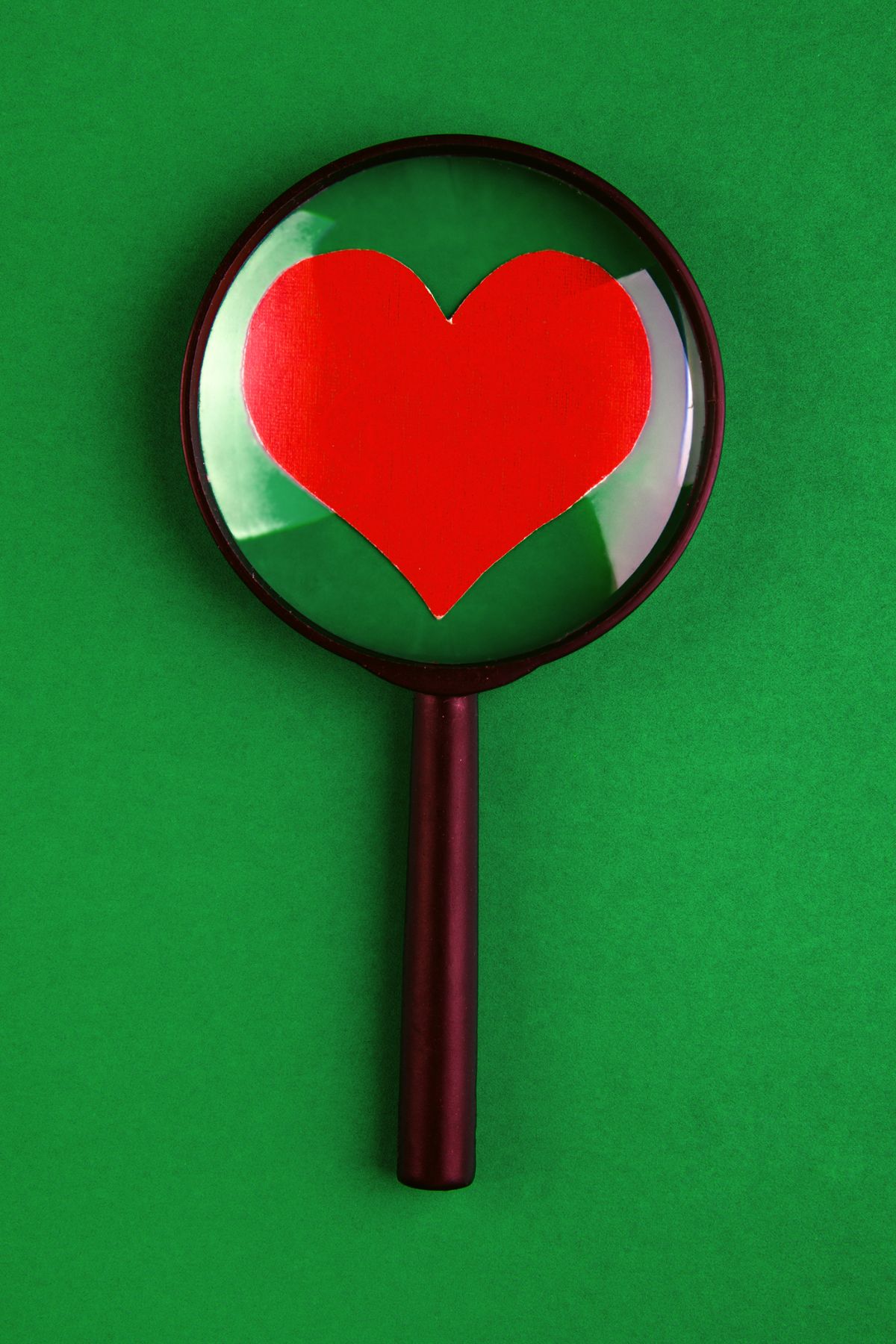 Magnifying glass with red heart on a green background