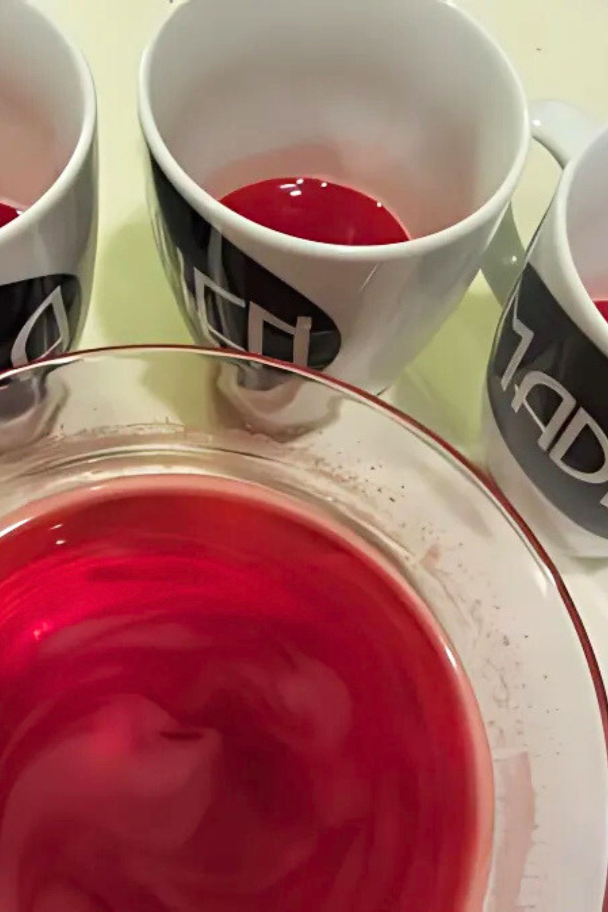 Bowl of red jello with three mugs