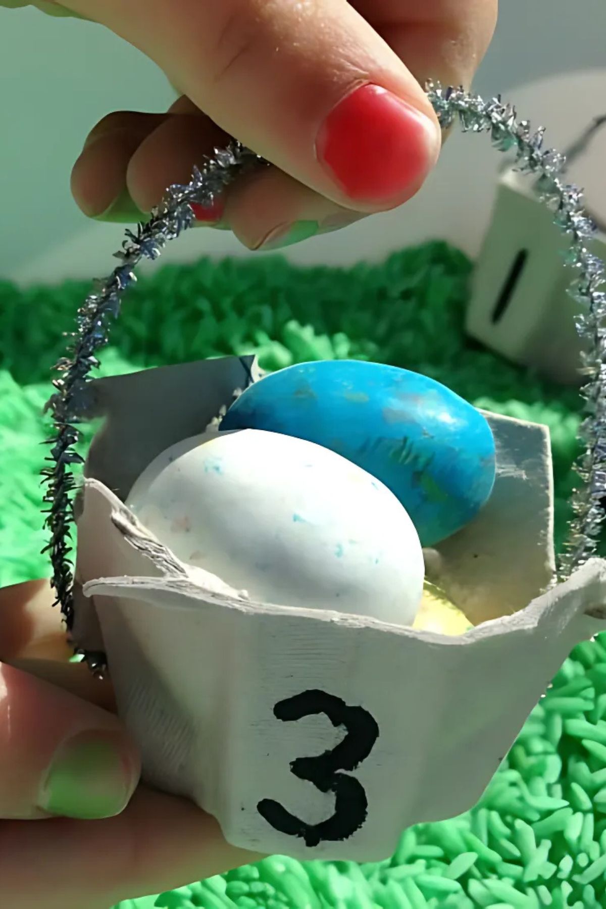 section of egg carton cut to form a small basket with a pipe cleaner handle and colorful candy eggs