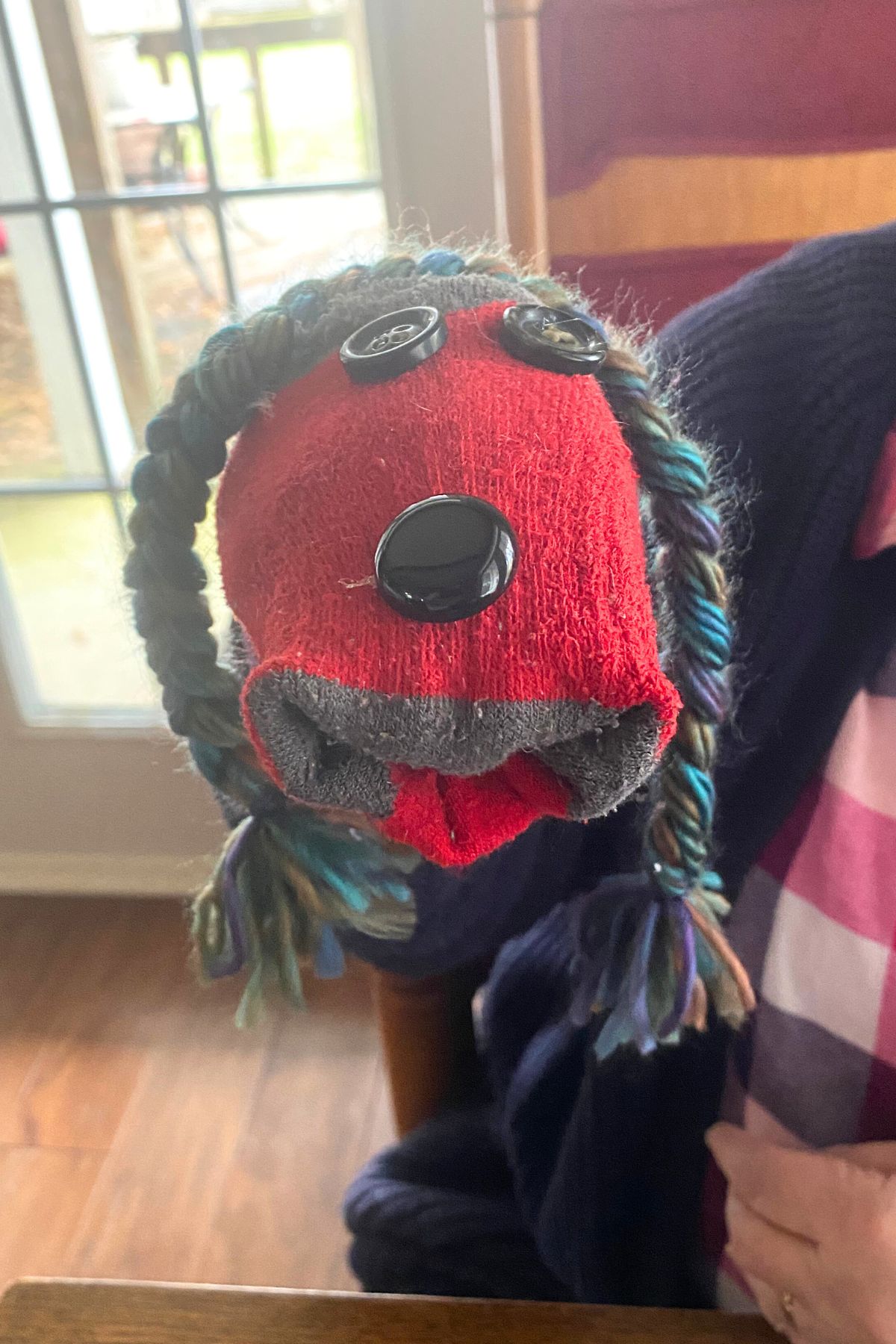 Red sock puppet with dark button eyes and nose and yarn hair