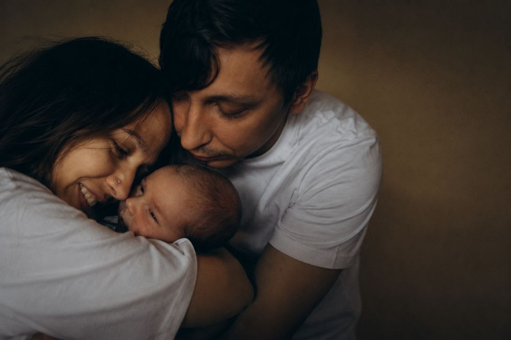 Parents hugging their infant baby