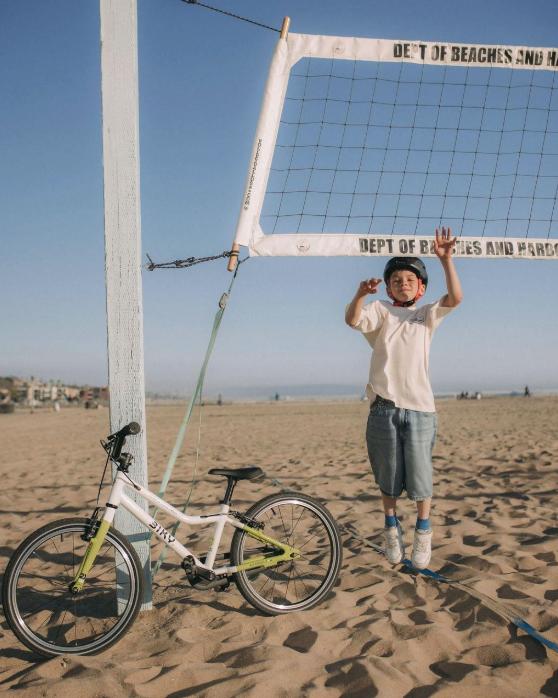 A child plays near a parked balance bike on the sand at the beach Playground Circuit 