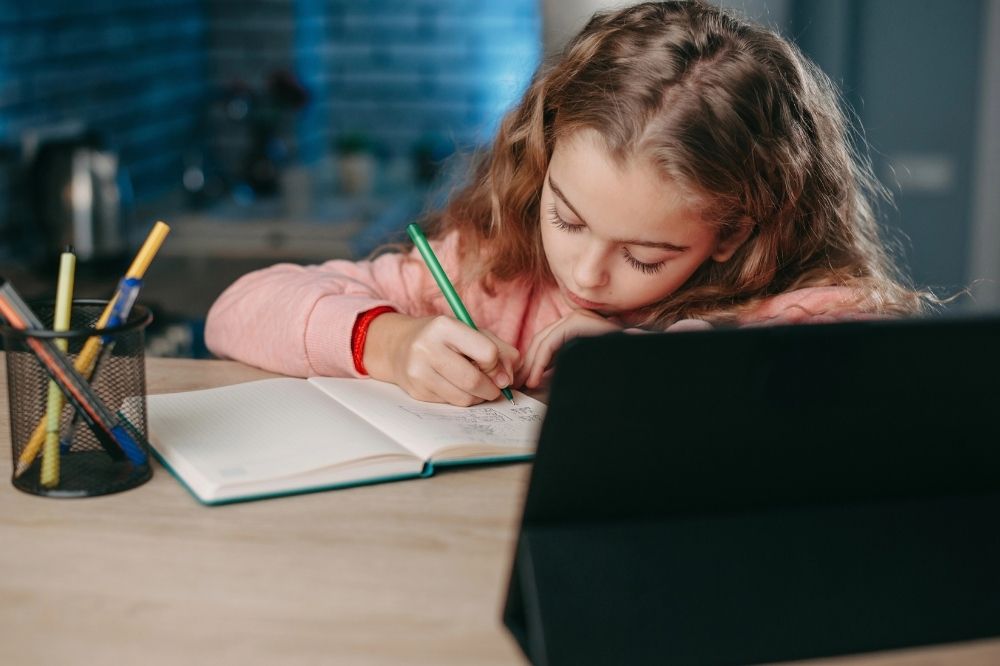 A kid writing on her notebook