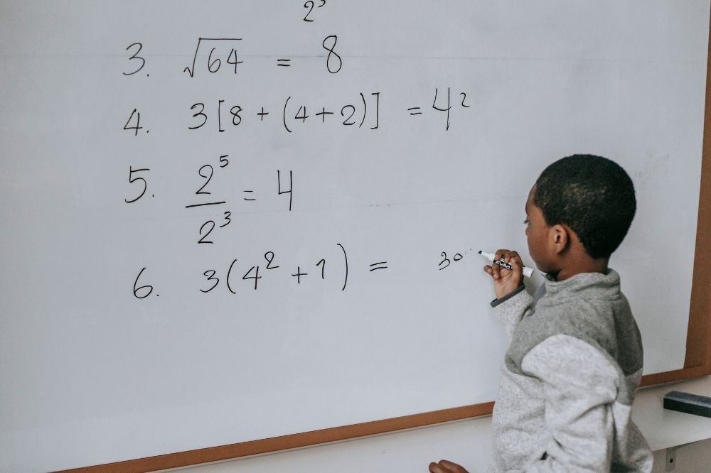 A young boy solving math problem in the board