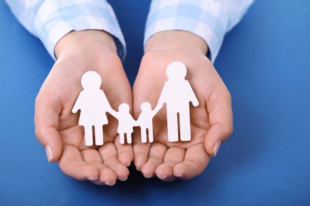 Family paper dolls in a hand