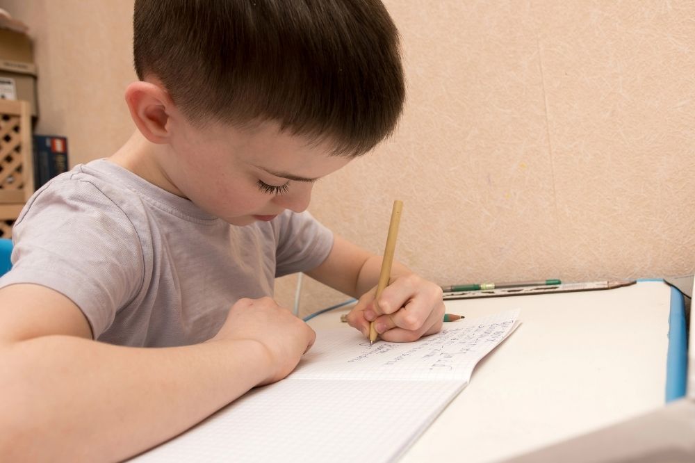 a young boy writing on his notebook