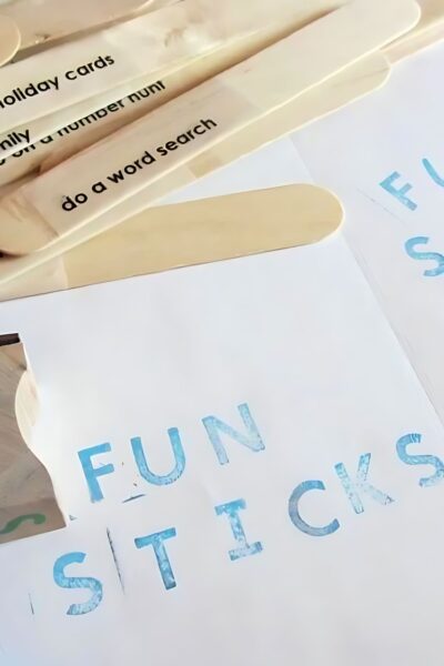 Popsicle sticks with an activity suggestion on each in a pile next to a piece of paper that is stamped with the words fun sticks