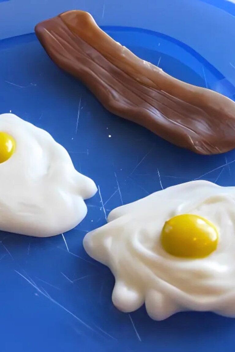 White chocolate "egg" whites with M&M yolks on a blue plate with tootsie roll and caramel "bacon"