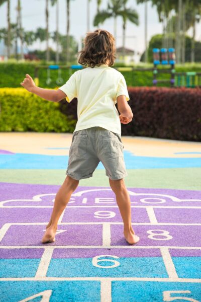 Child in a yellow shirt playing hopscotch