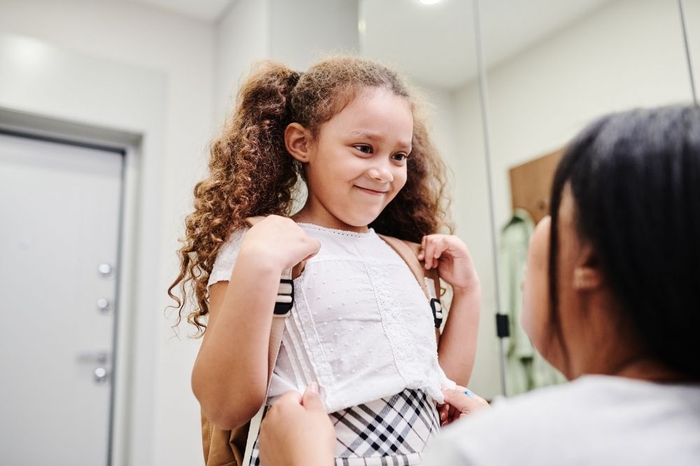 A young girl with curly hair ready for school