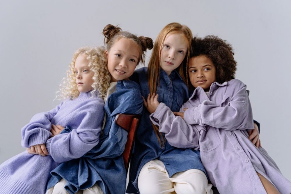 The girls are sitting on chairs, hugging and posing for the camera