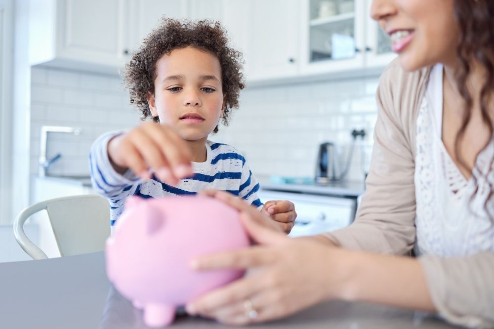 A kid dropping coins into a piggy coin bank