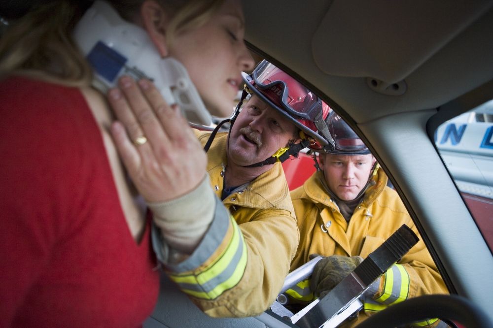 A woman in a car accident and medical responders are helping her