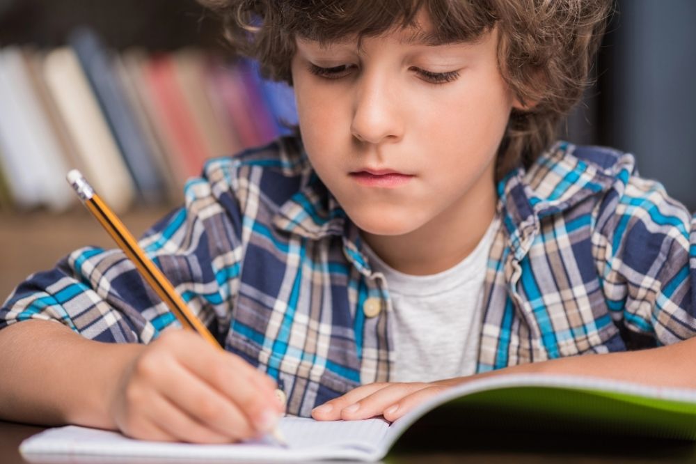 A young boy writing in his notebook
