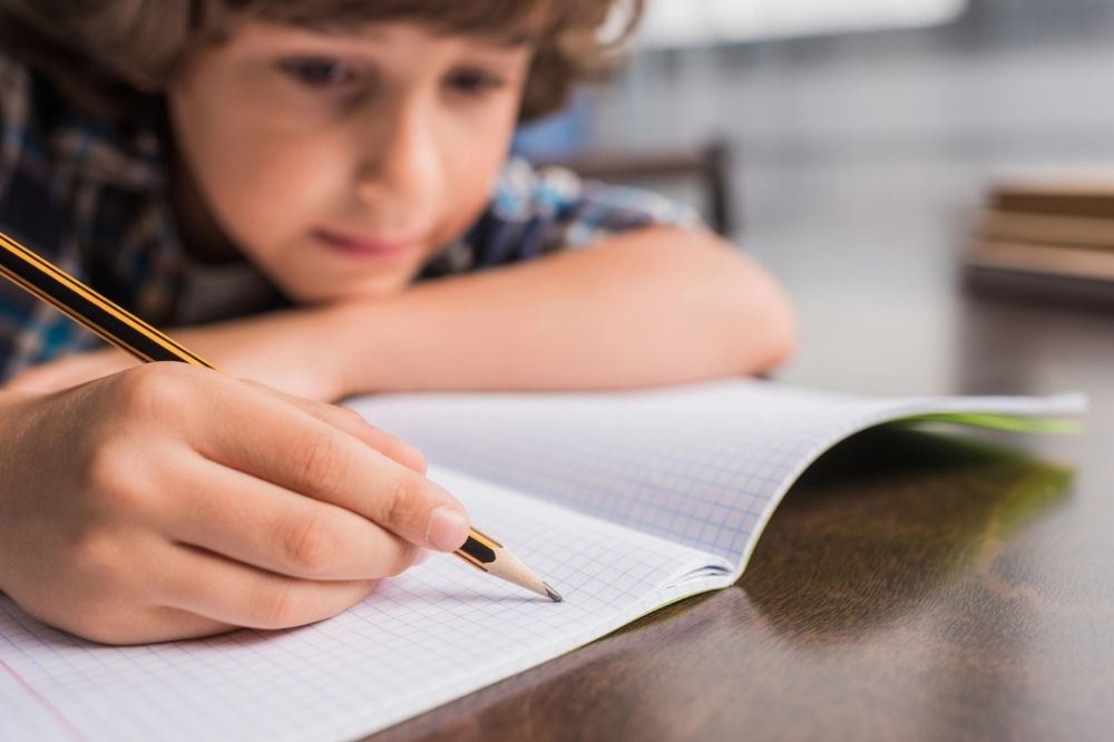 Boy is thinking what to write in his notebook