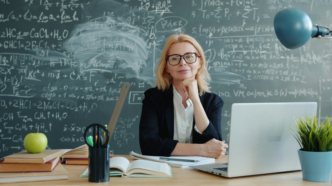 Smiling teacher sitting at a classroom desk