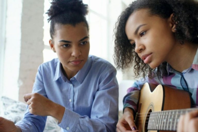 Music Teacher teaching guitar lesson to a teen